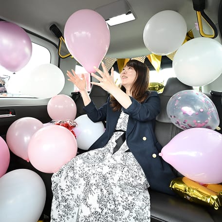 風船で装飾された車内を楽しむ女性